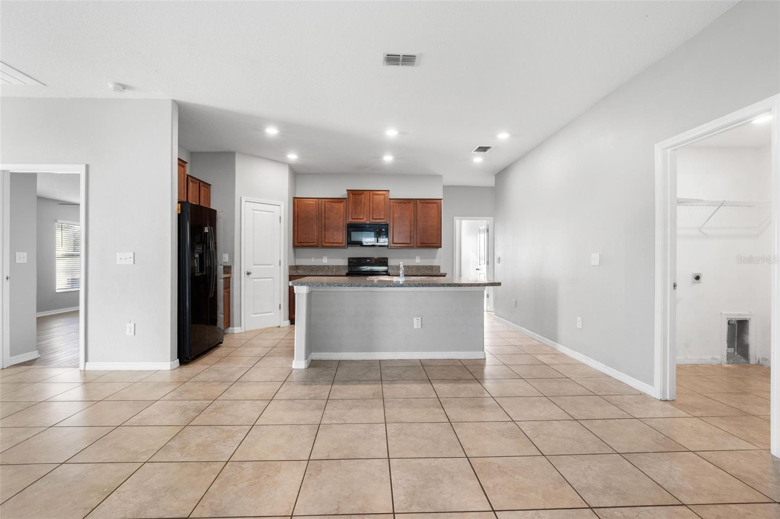Granite countertops extend along both sides of the kitchen, providing generous prep space, abundant cabinetry, and an efficient layout designed to maximize functionality.