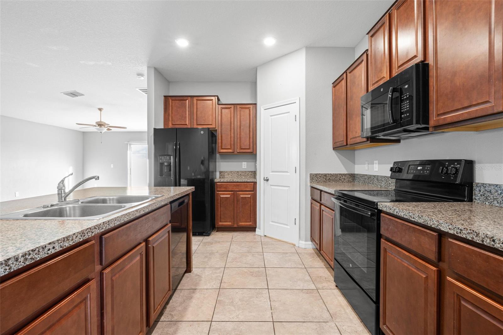 Granite countertops extend along both sides of the kitchen, providing generous prep space, abundant cabinetry, and an efficient layout designed to maximize functionality.