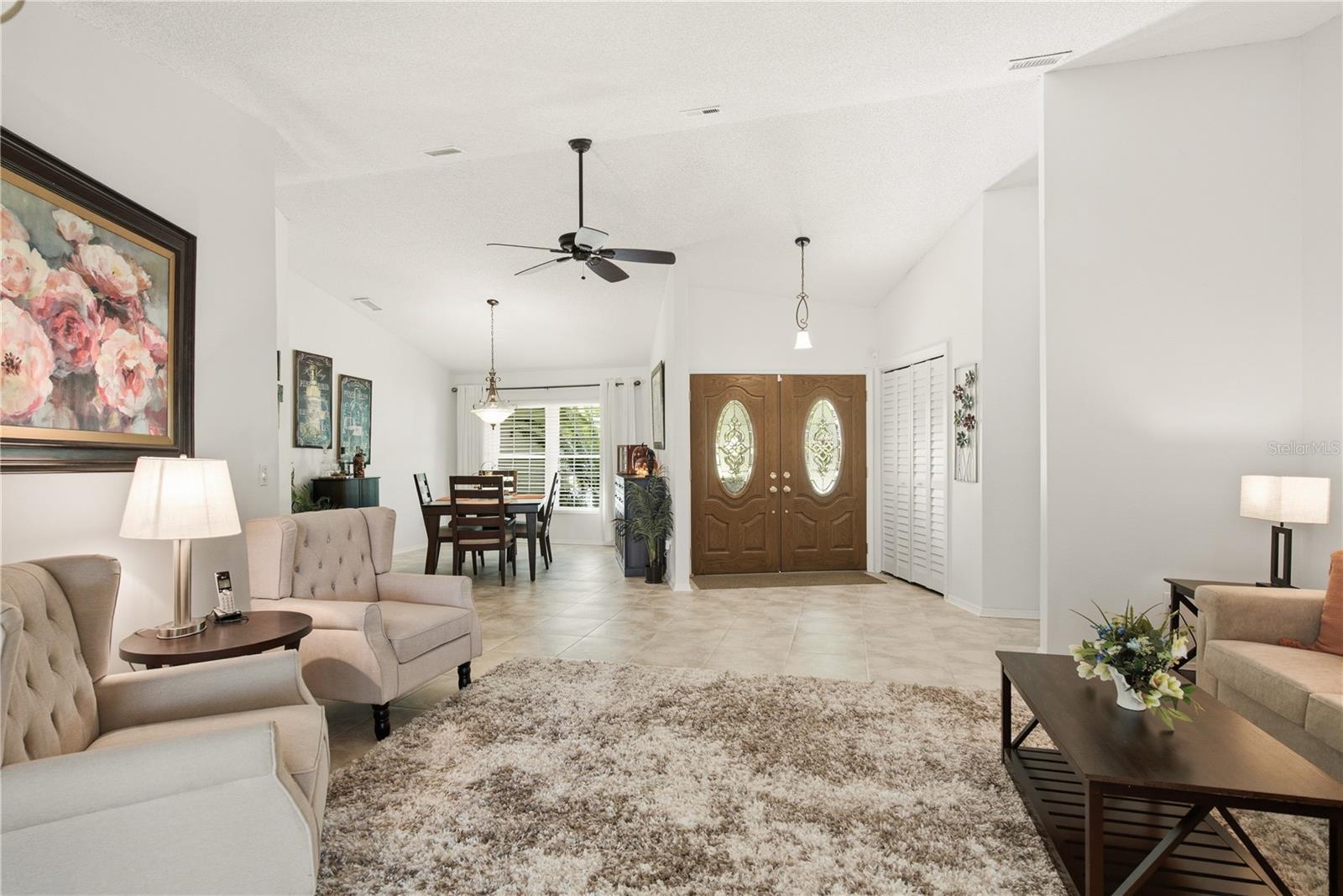 Spacious open concept layout looking back from the living room toward the welcoming foyer and formal dining area.