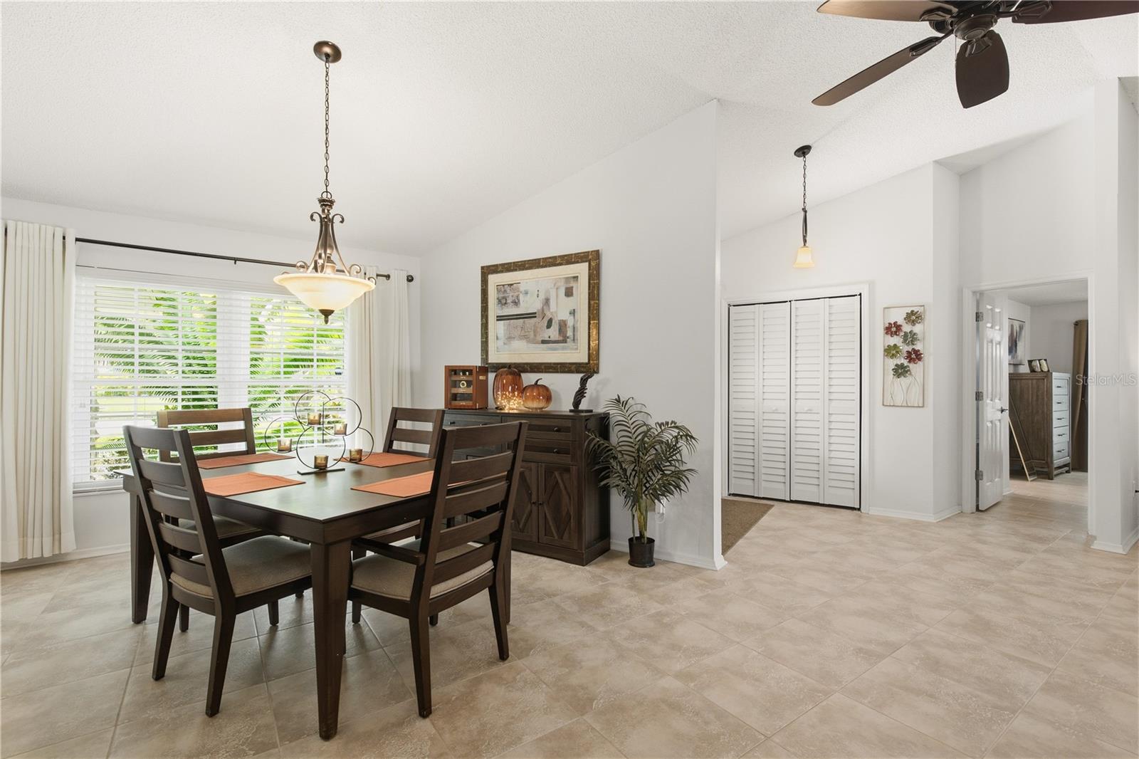 Another view of the formal dining area showcasing the seamless flow into the foyer, vaulted ceilings, and a large window that floods the space with natural light.