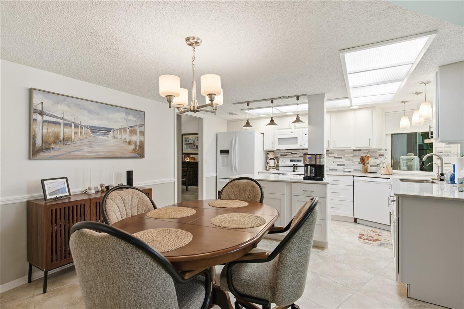 Charming casual dining area situated right next to the bright kitchen, featuring white cabinetry, modern appliances, and stylish light fixtures.