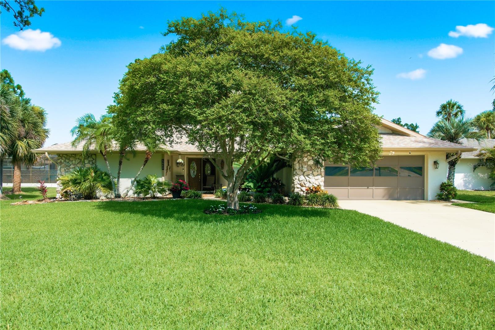 Charming front exterior featuring a lush, manicured lawn and mature shade trees welcoming you home.