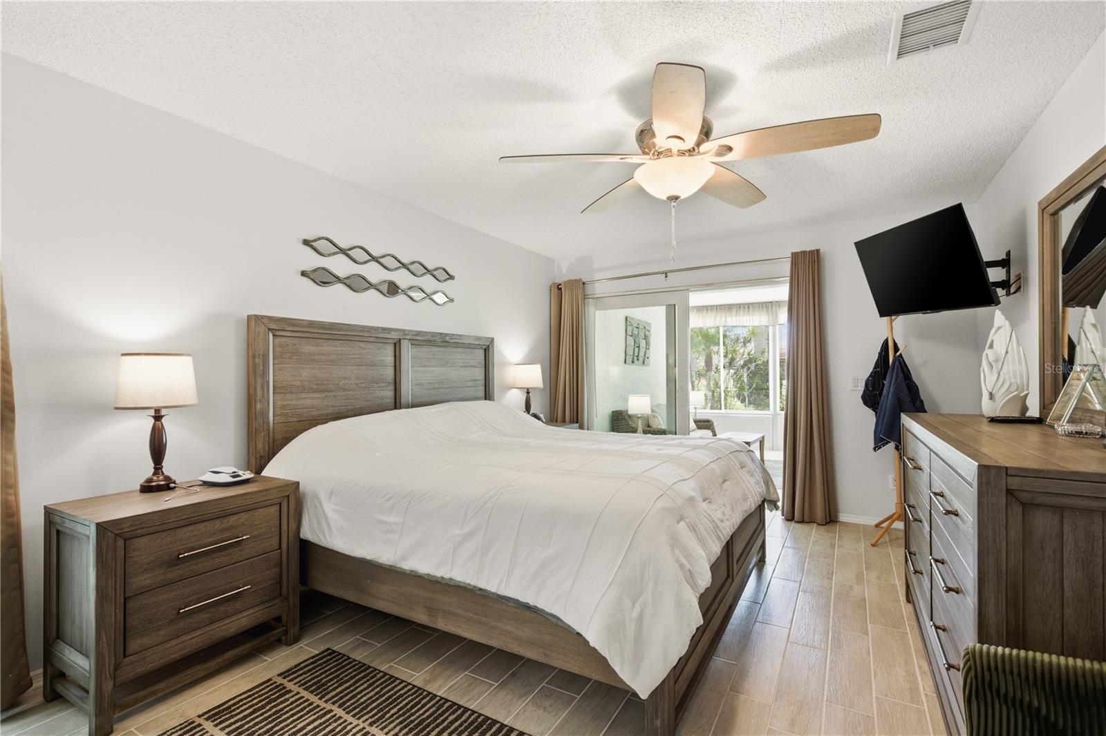Spacious primary bedroom featuring a lighted ceiling fan and sliding glass doors that open right into the climate controlled Florida Room.