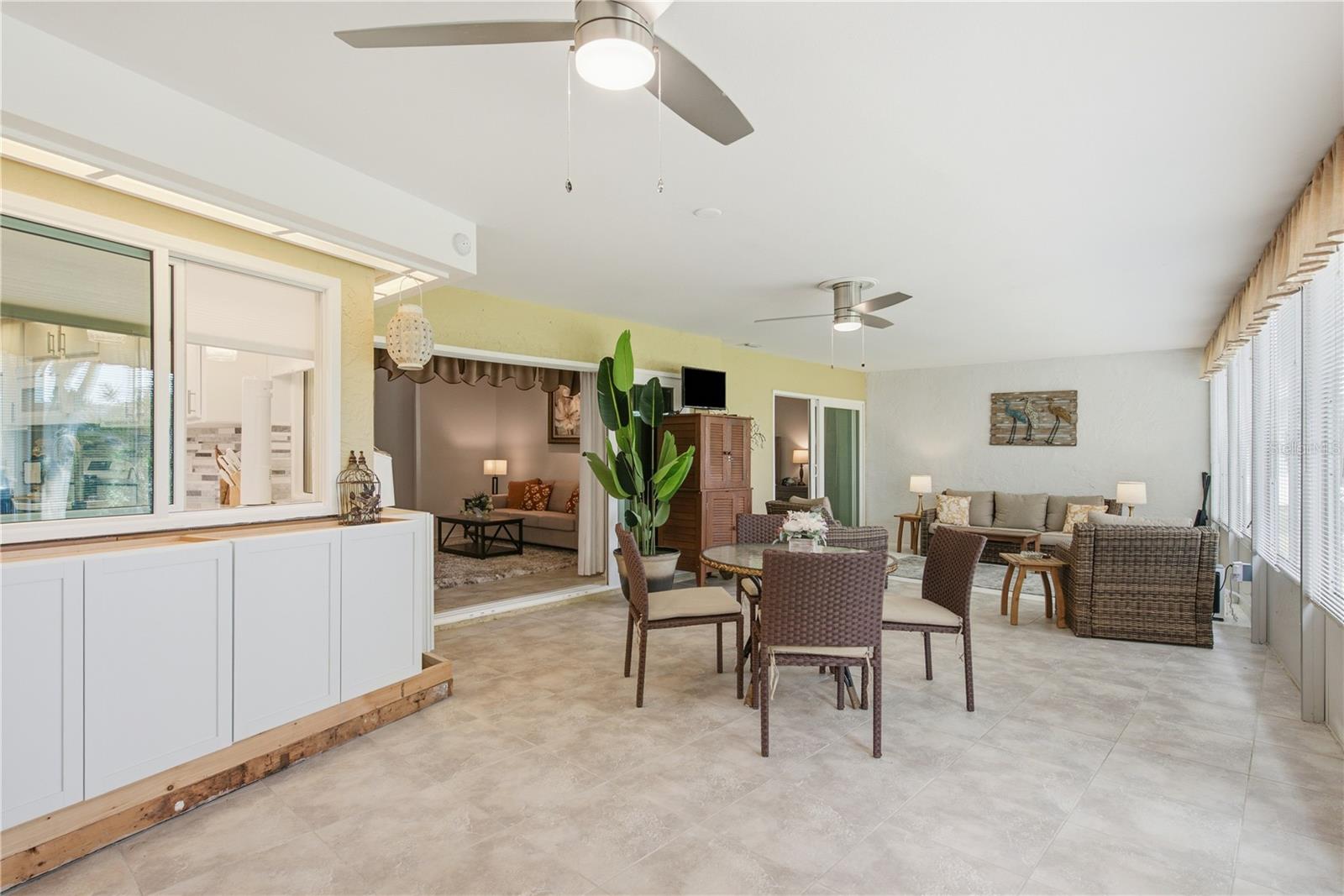 Massive, climate controlled Florida Room featuring tile floors, multiple ceiling fans, a casual dining area, and a large living setup that seamlessly connect back into the main house.
