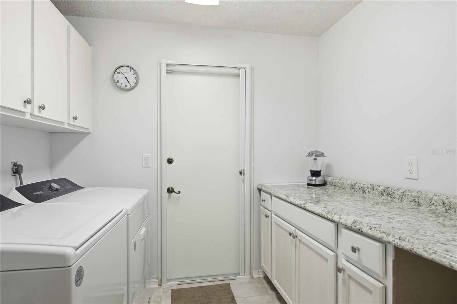 Convenient indoor laundry room complete with washer and dryer, upper storage cabinets, and a spacious folding counter with extra lover cabinetry.