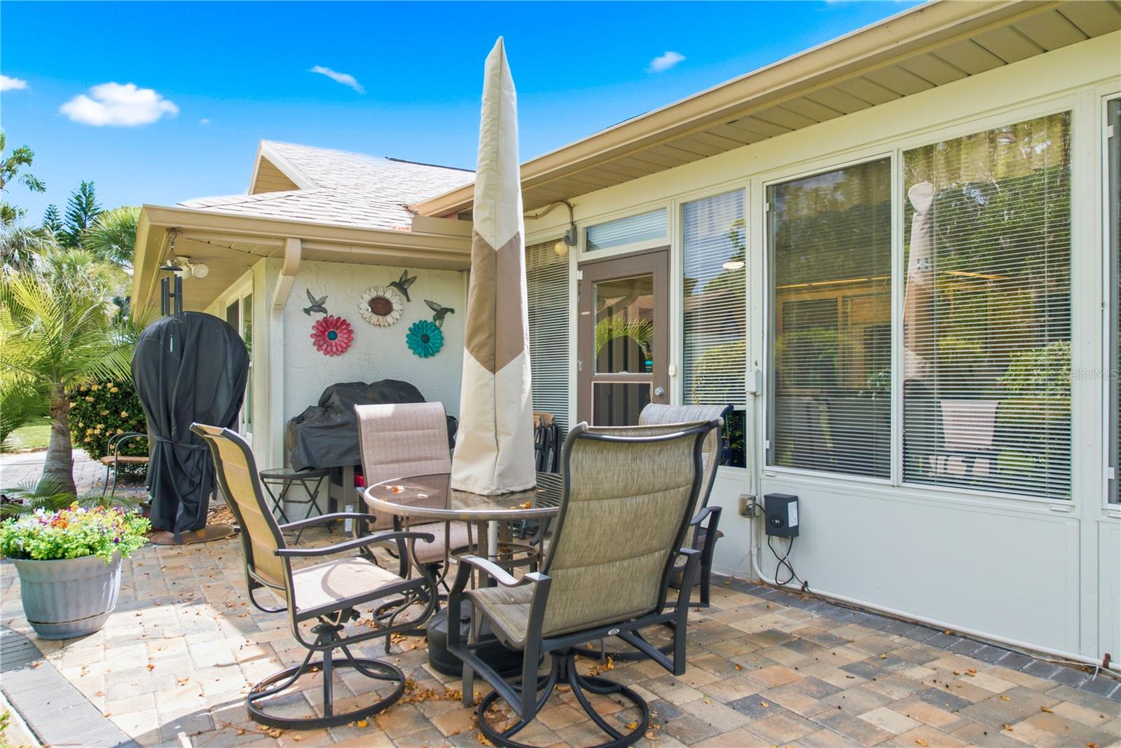 Spacious rear brick paver patio setup perfect for entertaining. Outdoor furniture and grill stay with the home!