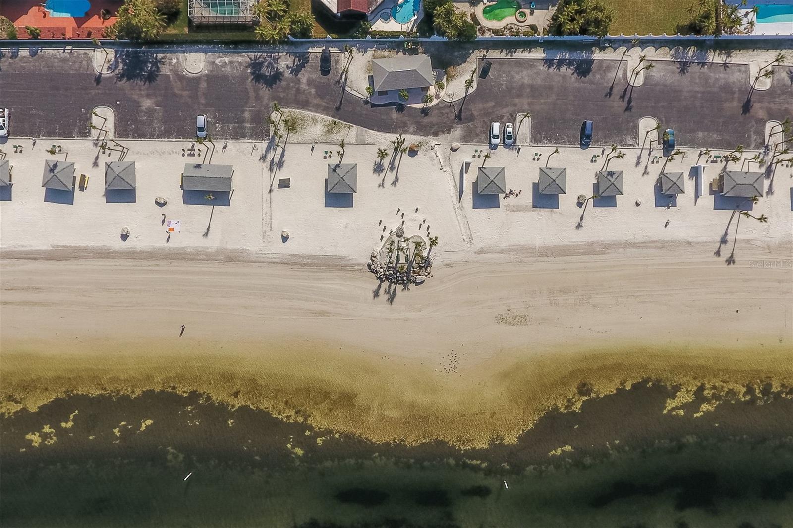 Ariel view of the exclusive private beach for residents of Gulf Harbors Woodlands, complete with shaded beach cabanas and easy parking.