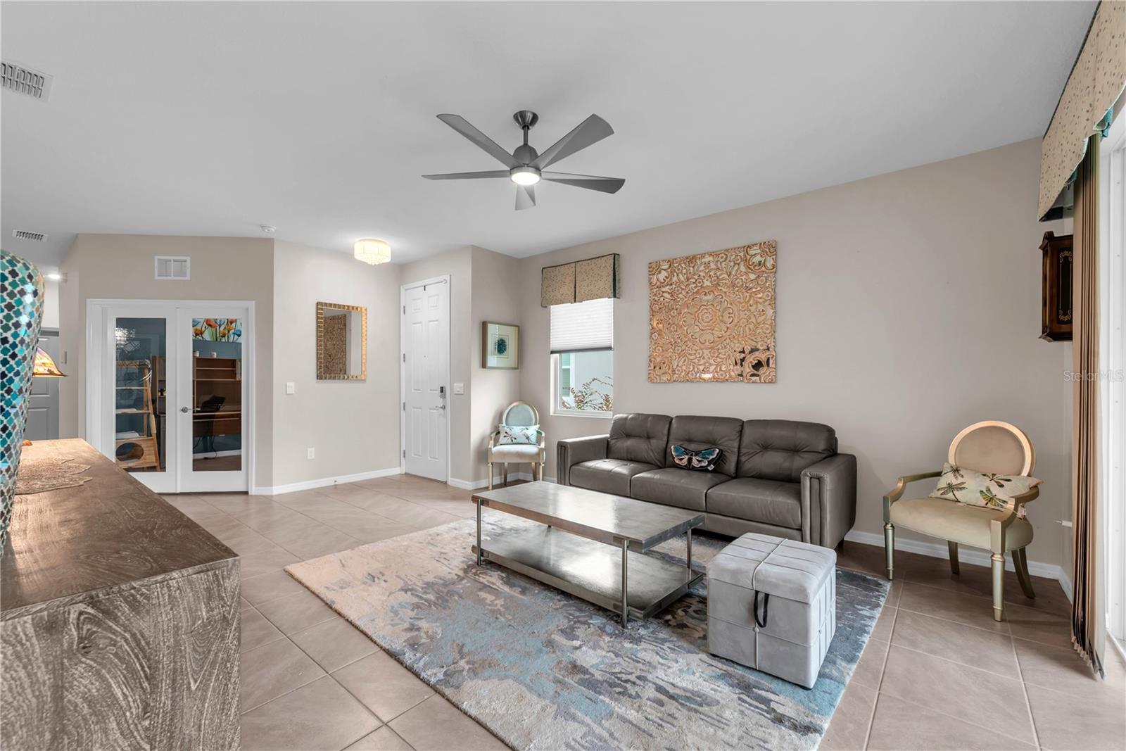The glass double french doors lead to a bedroom or den/office space with a walk-in closet.