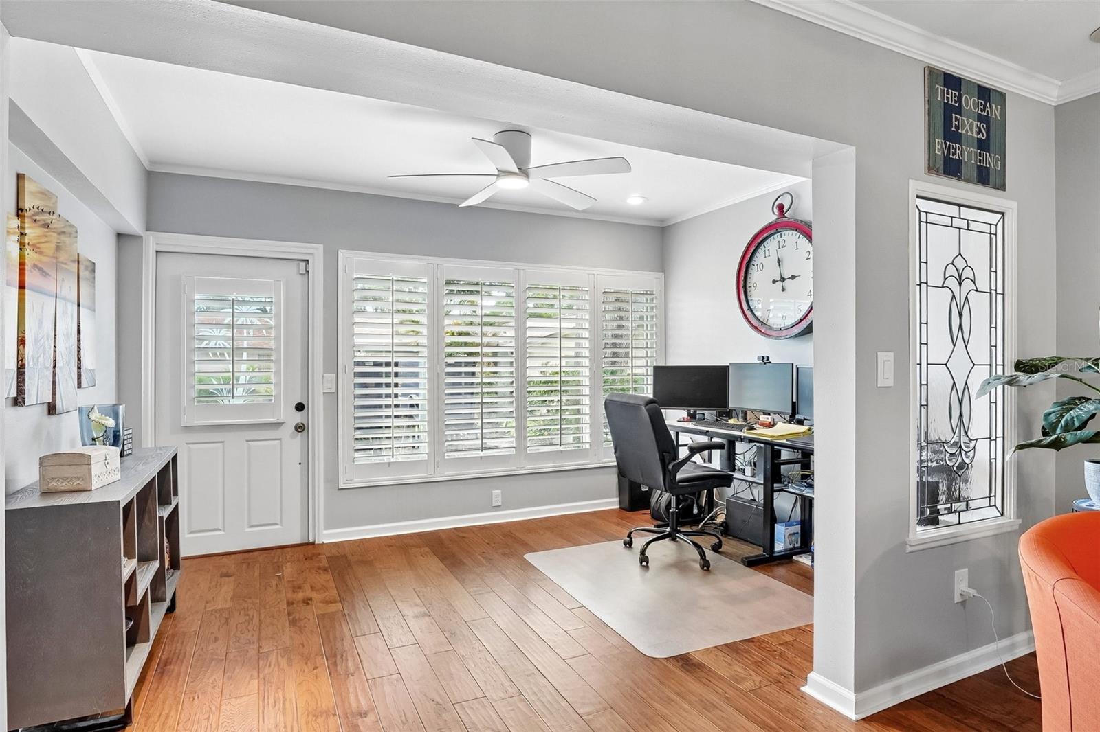 Sunroom / flex space with wall of windows dressed with Key West style plantation shutters is ideal for office, morning coffee, reading or just relaxing.
