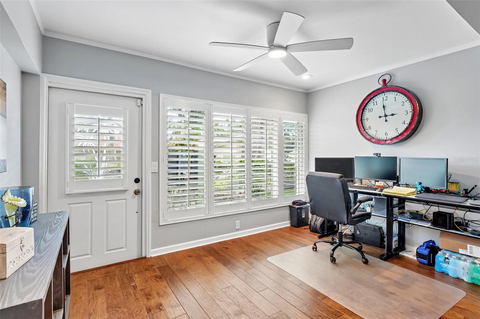 Sunroom / flex space with wall of windows dressed with Key West style plantation shutters is ideal for office, morning coffee, reading or just relaxing.