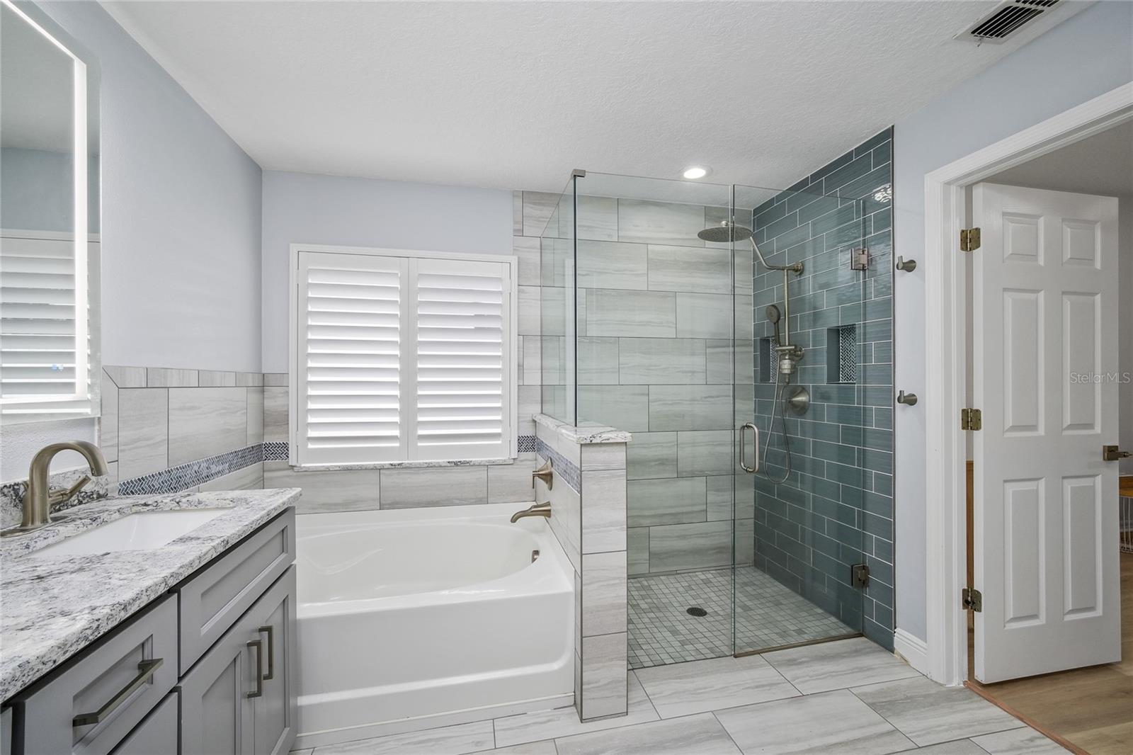 Remodeled primary bath with soaking tub and frameless glass shower