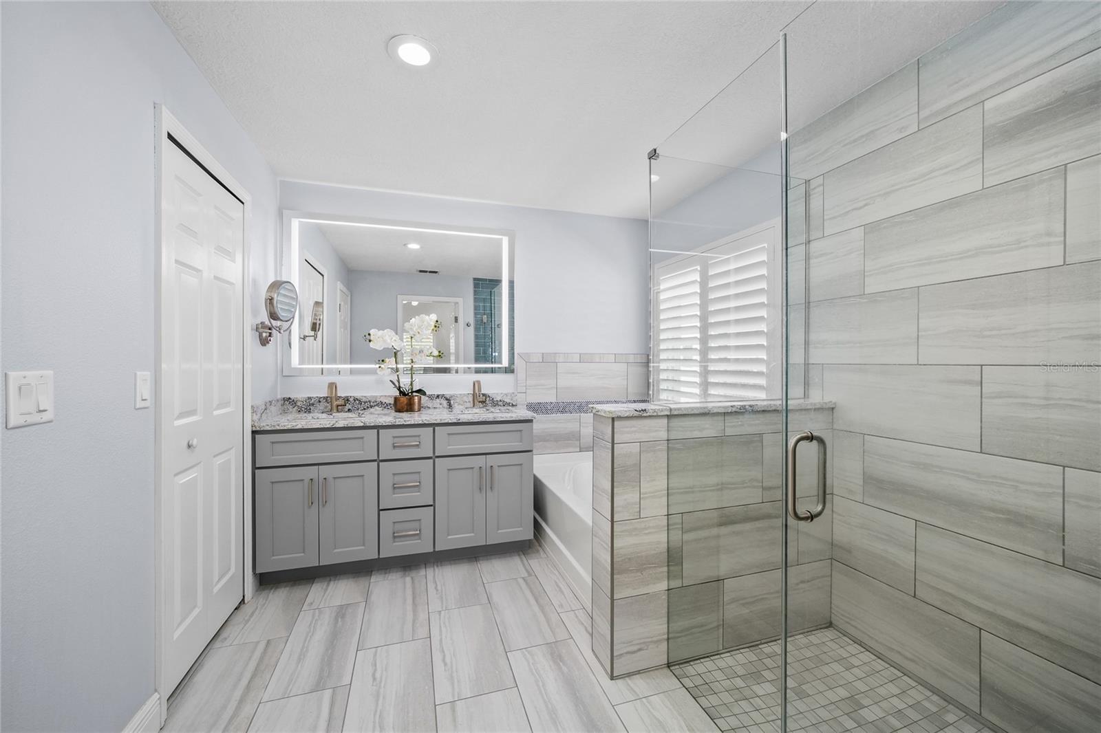 Remodeled primary bath with soaking tub and frameless glass shower