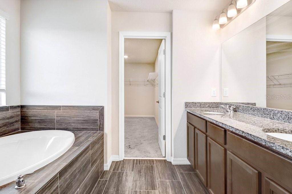 Primary Bathroom with soaking tub, walk in shower, duel sink vanity and beautiful wood plank tiles