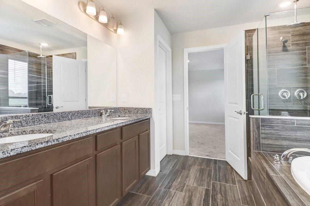 Primary Bathroom with soaking tub, walk in shower, duel sink vanity and beautiful wood plank tiles