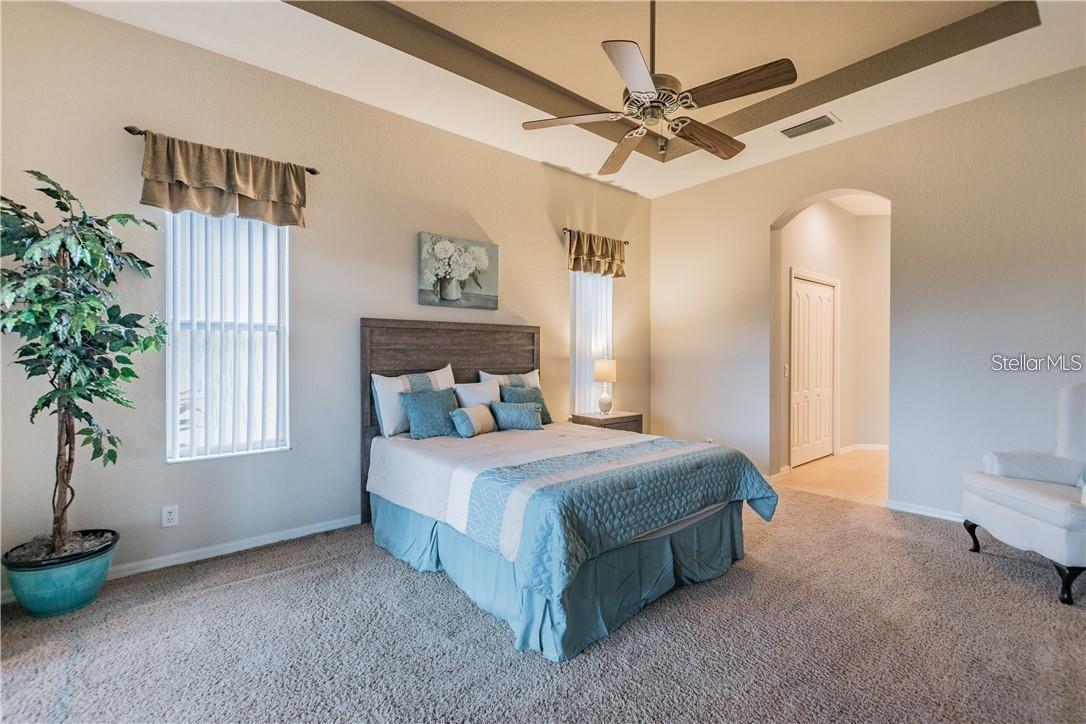 Master bedroom with tray ceiling with entrance to closets and bathroom