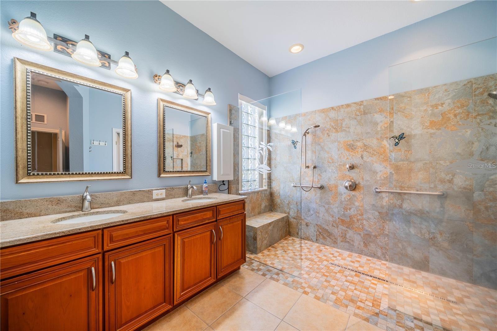 Master bath with double sinks and beautiful walk in shower featuring elegant marble countertops, and custom tile work
