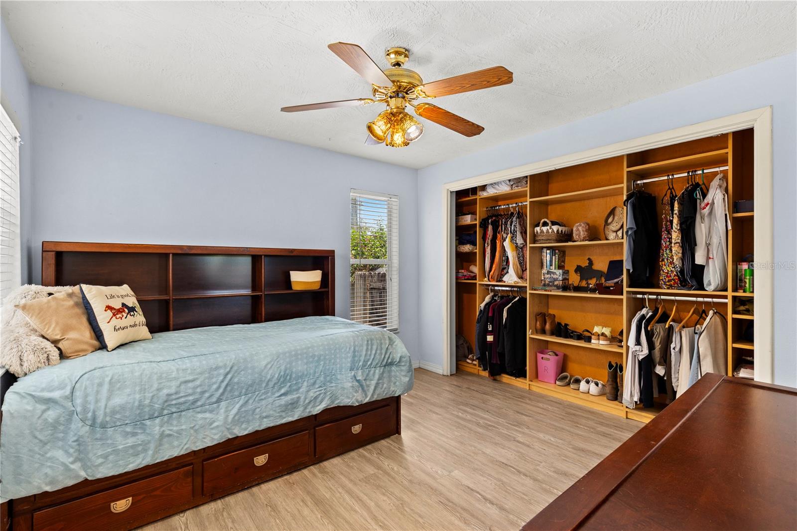 Well-appointed second bedroom featuring abundant natural light and a custom closet organizer designed to maximize storage and keep everything neatly arranged.