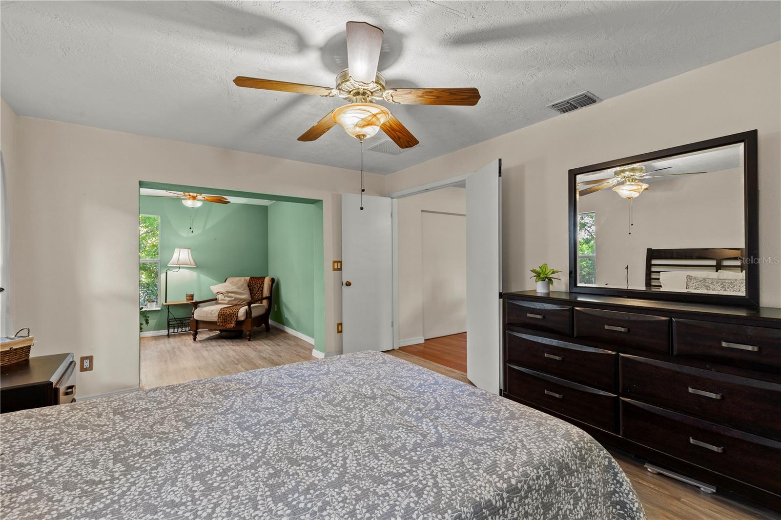 Spacious primary bedroom retreat featuring a bright and airy layout with a comfortable sitting area, creating the perfect space for relaxation and privacy. The room offers abundant natural light and a peaceful atmosphere, ideal for an owner’s suite designed for comfort and everyday living.