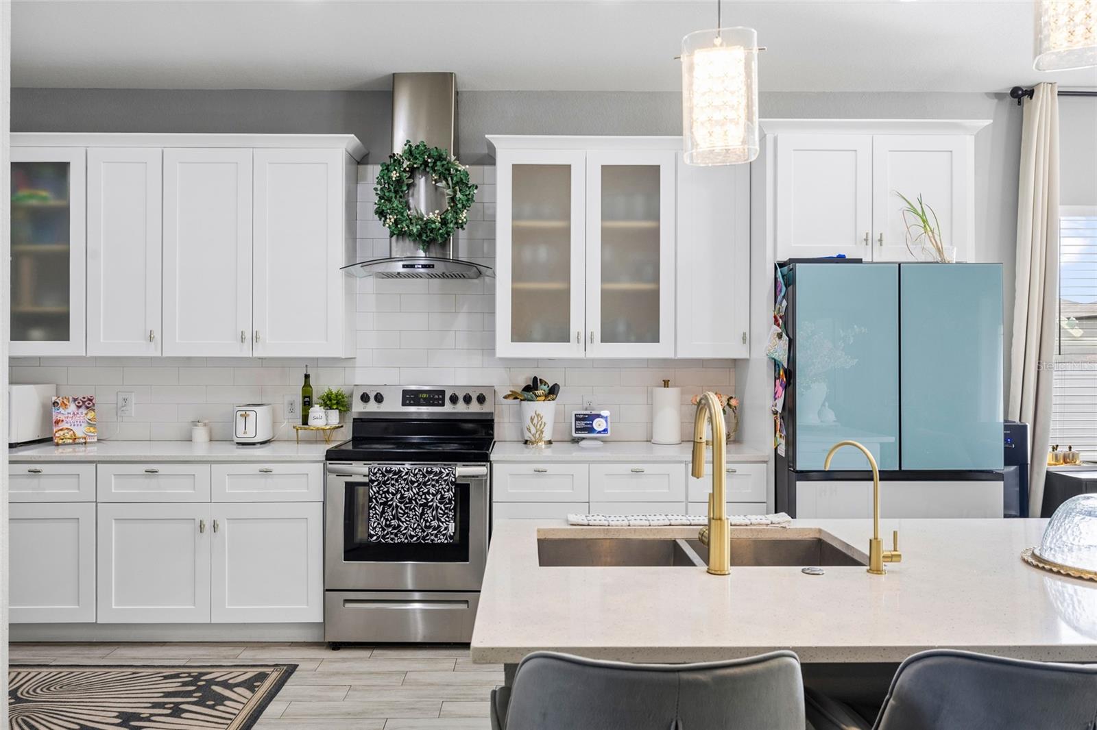 Fully renovated kitchen featuring quartz countertops, white shaker cabinets, stainless steel appliances, and oversized island seating