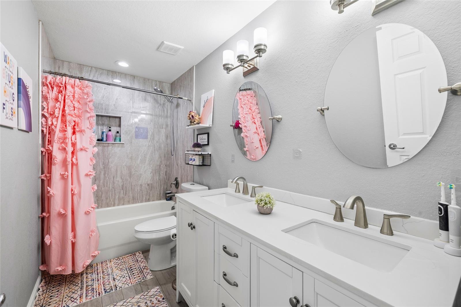 Beautifully updated secondary bathroom with quartz counters, dual sinks, and designer tile work