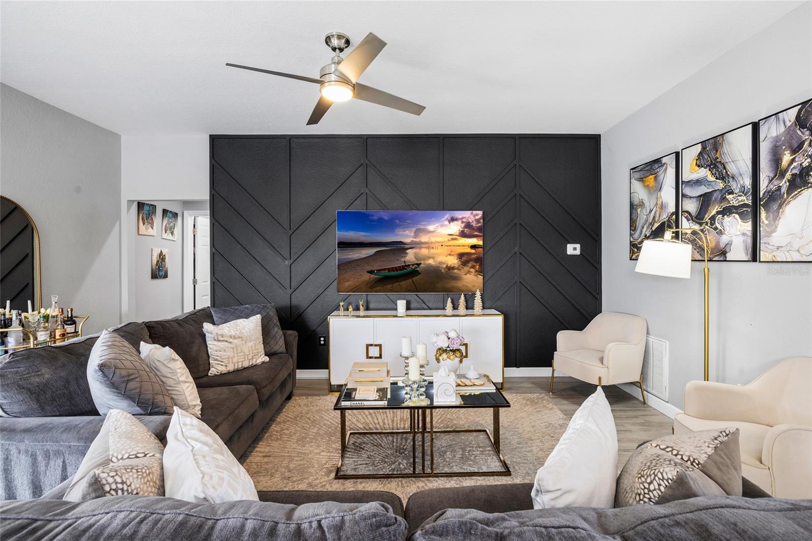 Spacious open-concept living room with designer accent wall and seamless flow to the kitchen and dining areas.