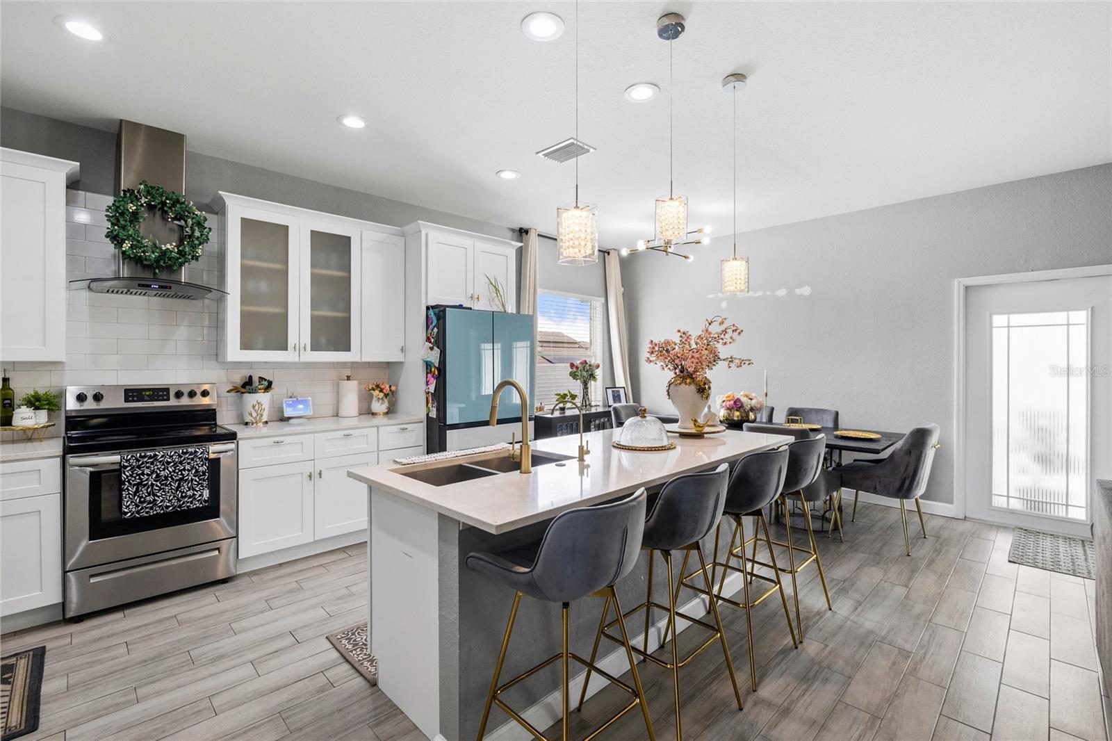 Fully renovated kitchen featuring quartz countertops, white shaker cabinets, stainless steel appliances, and oversized island seating