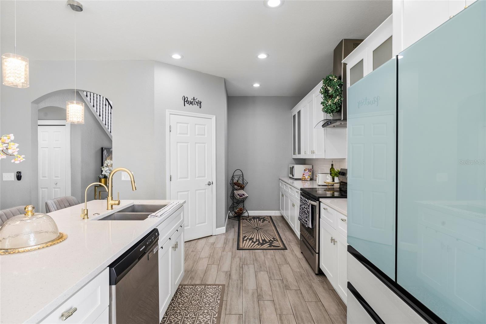 Fully renovated kitchen featuring quartz countertops, white shaker cabinets, stainless steel appliances, and oversized island seating