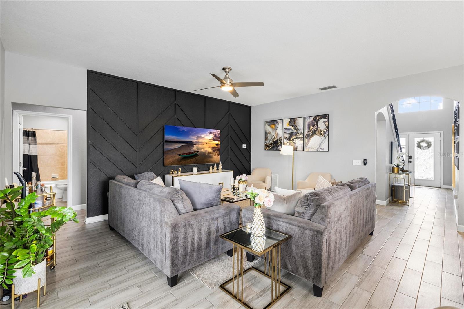 Spacious open-concept living room with designer accent wall and seamless flow to the kitchen and dining areas.