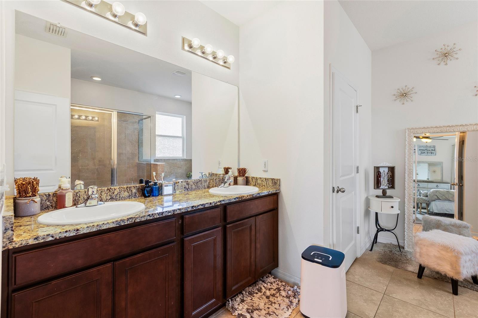 The luxurious primary bathroom includes a double-sink granite vanity, soaking garden tub, separate walk-in shower, and ample storage space, creating a spa-like atmosphere for everyday comfort and relaxation.