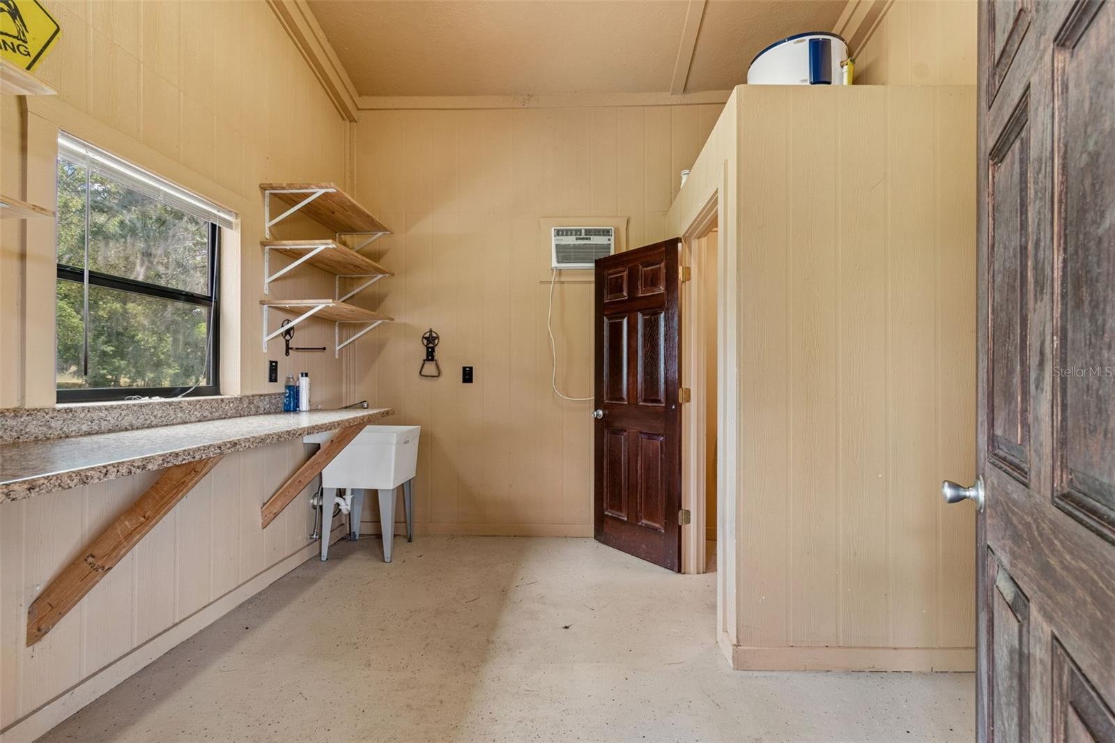 Feed room with utility sink, hot water heater, and toilet