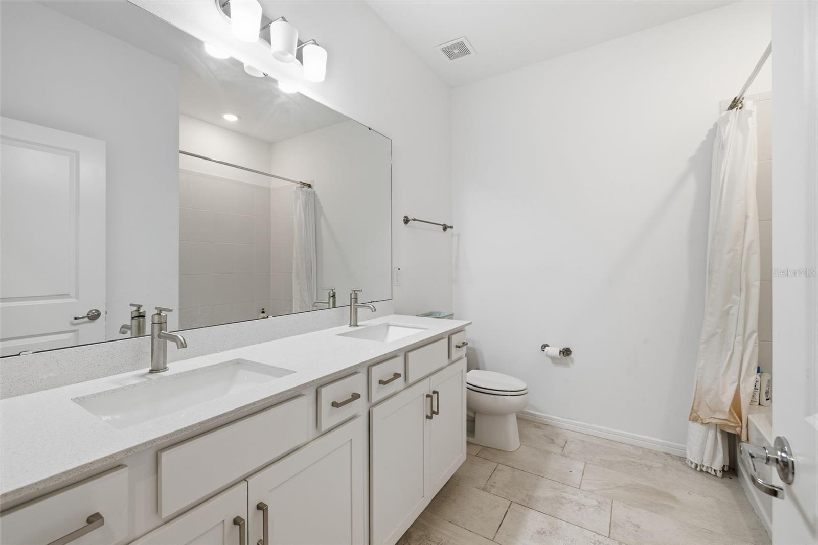 Downstairs hall bathroom with double Quartz sink vanity and shower/tub combo