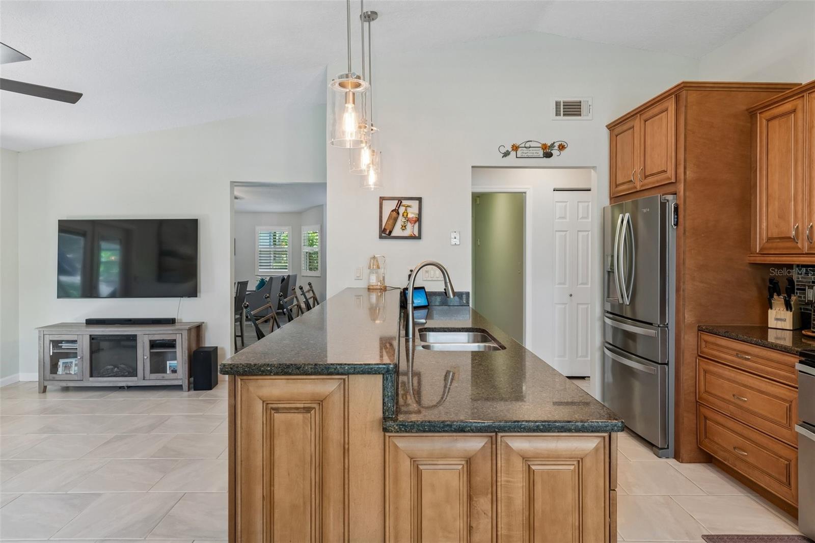 The eat-in kitchen is beautifully appointed with stainless steel appliances, granite countertops, breakfast bar seating, cabinet pullouts, soft-close drawers, and a cheerful breakfast nook surrounded by windows.