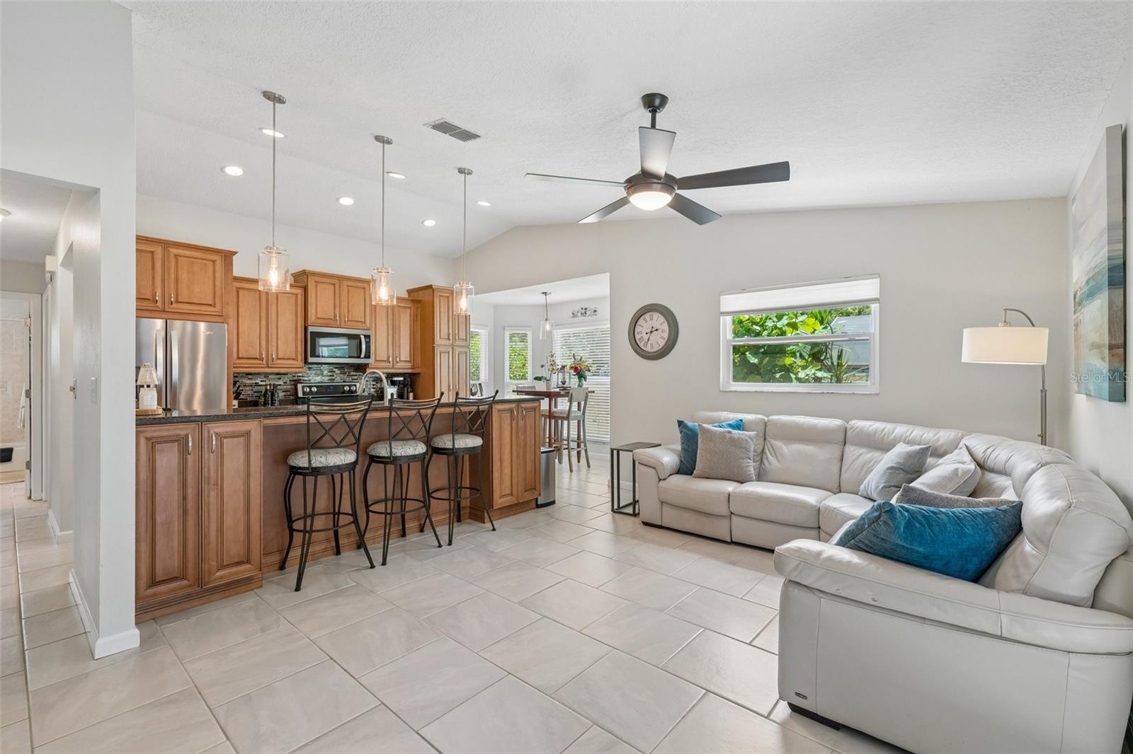 The kitchen opens to the family room, creating a connected everyday living space with tile flooring, vaulted ceilings, and French doors leading out to the patio.