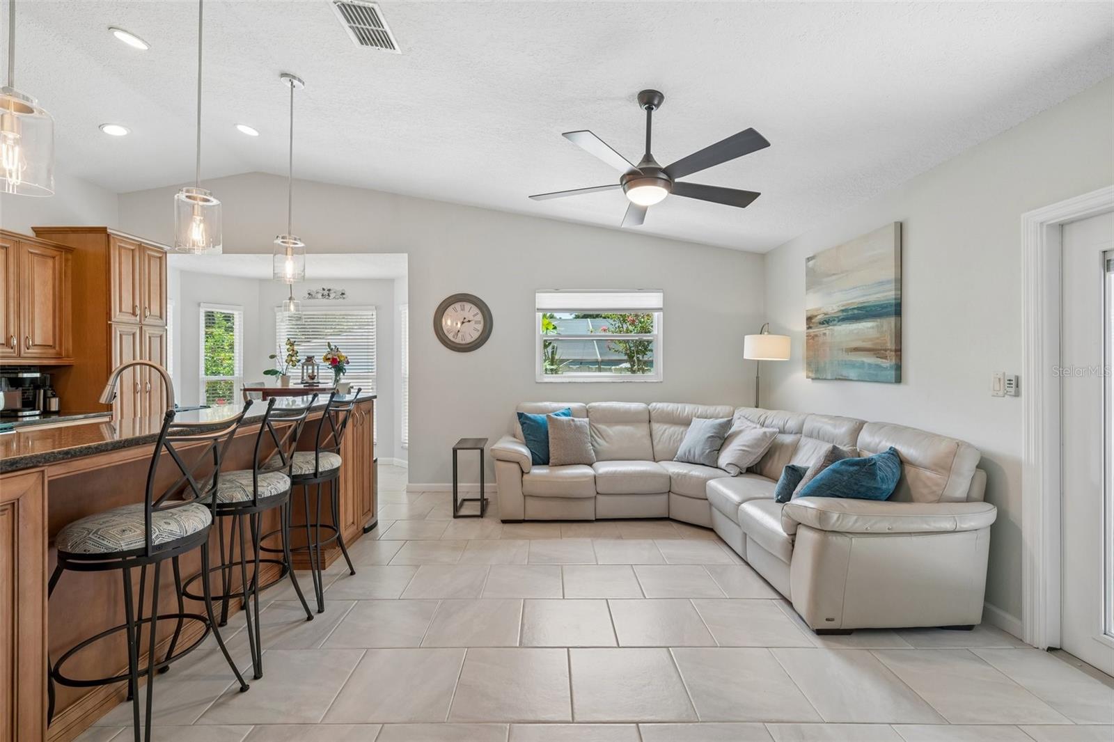 The kitchen opens to the family room, creating a connected everyday living space with tile flooring, vaulted ceilings, and French doors leading out to the patio.