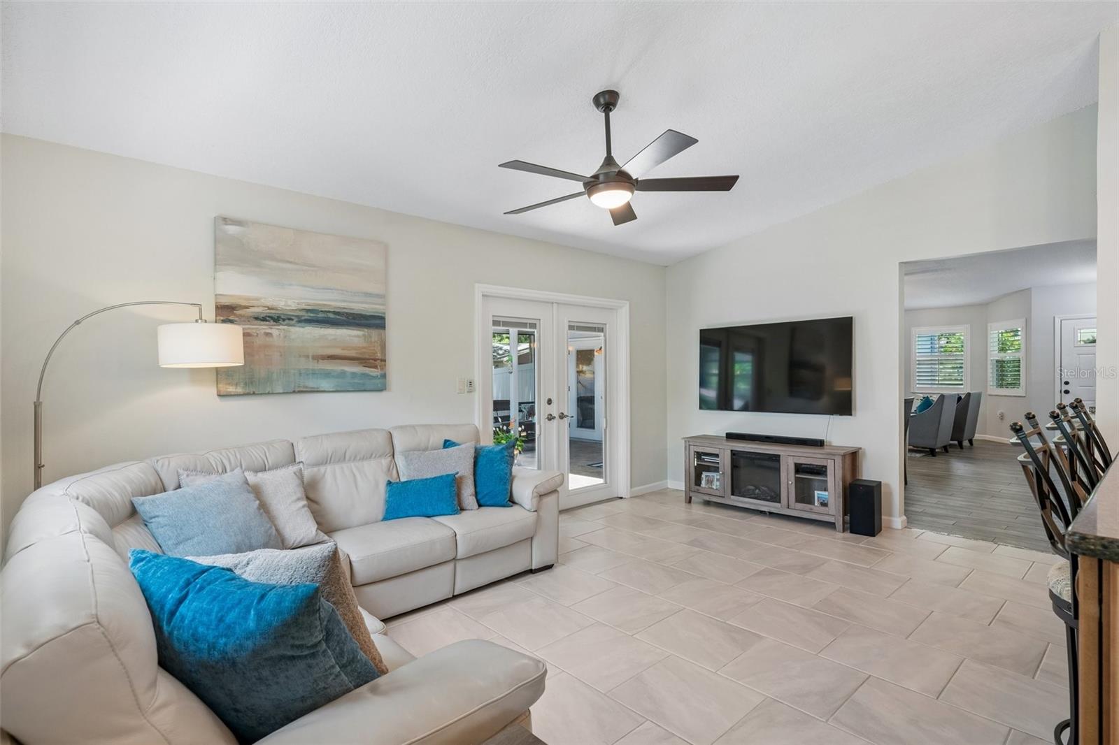 The kitchen opens to the family room, creating a connected everyday living space with tile flooring, vaulted ceilings, and French doors leading out to the patio.