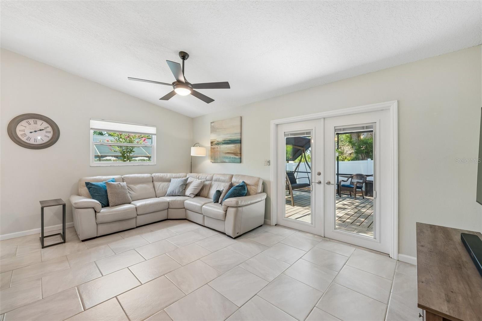 The kitchen opens to the family room, creating a connected everyday living space with tile flooring, vaulted ceilings, and French doors leading out to the patio.