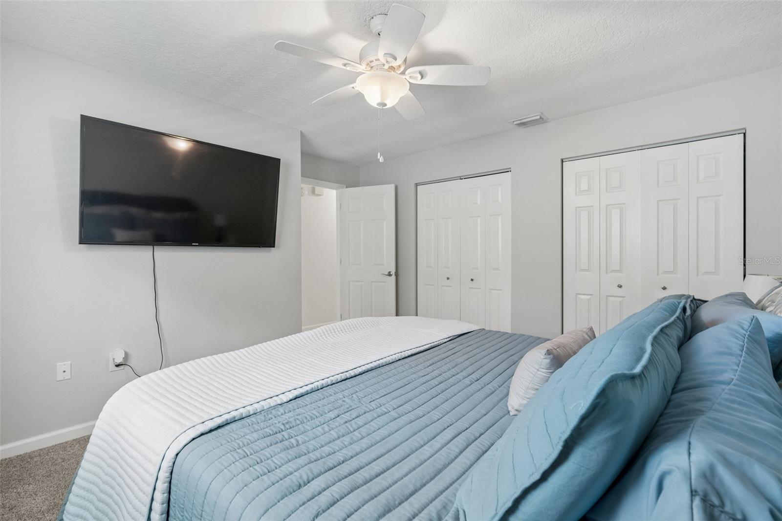 Second bedroom with wall of closets and neutral tones.