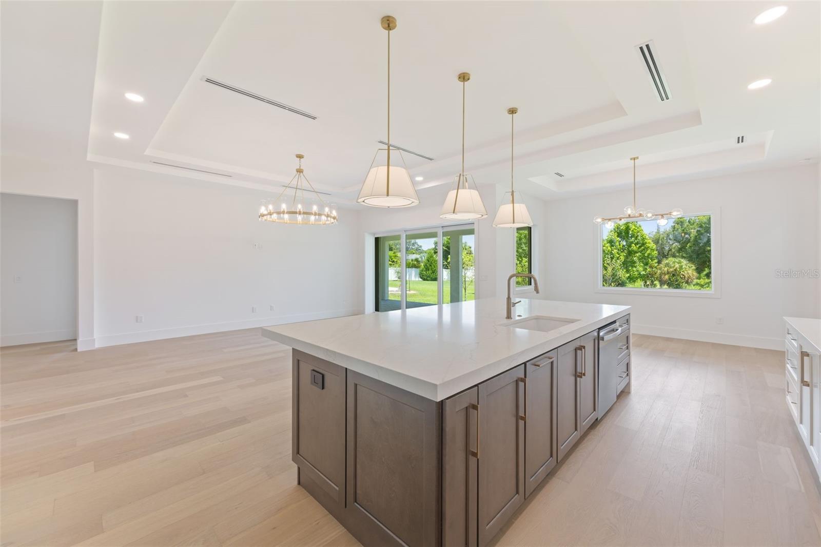 The gourmet kitchen is a true showpiece, featuring full-height custom cabinetry, an oversized 11-foot quartz island with storage on both sides, marble backsplash, GE Profile appliances, custom range hood, cooktop, wall oven, and soft-close cabinetry throughout.