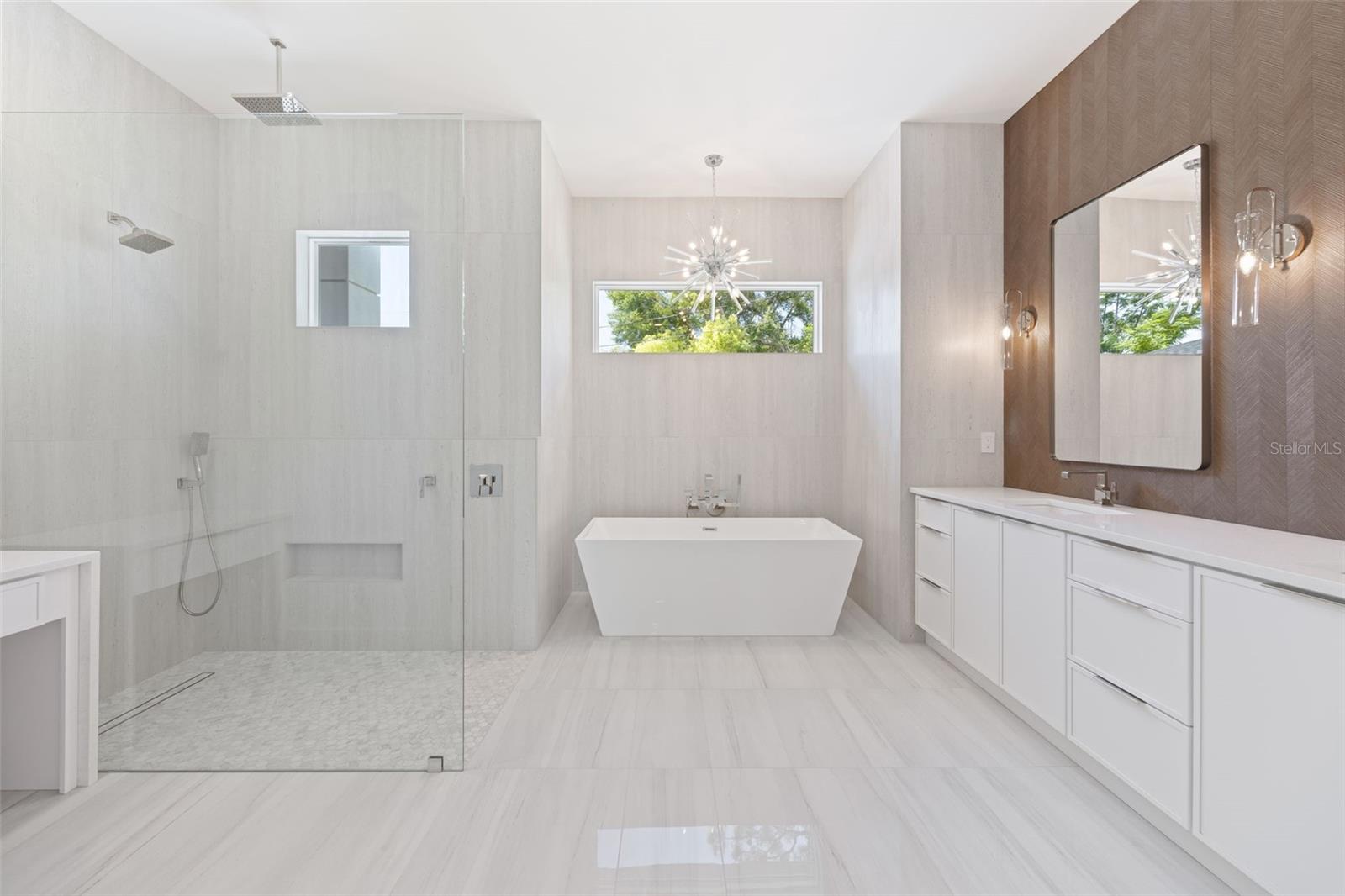 The luxurious primary suite offers a spa-inspired retreat featuring a freestanding soaking tub, oversized walk-in shower with rain head and handheld shower, premium Italian tile, designer fixtures, and thoughtful custom details throughout.