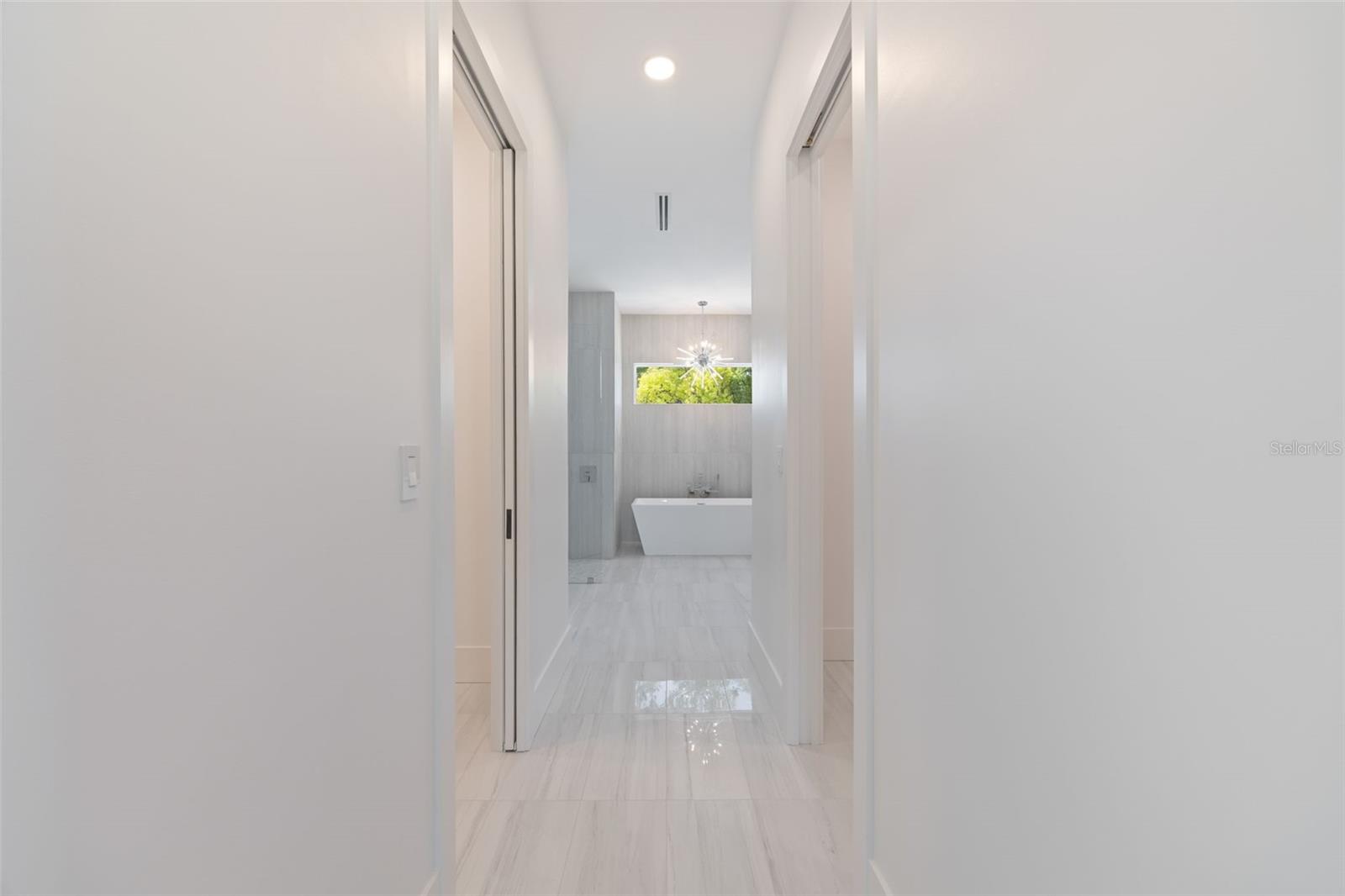 The luxurious primary suite offers a spa-inspired retreat featuring a freestanding soaking tub, oversized walk-in shower with rain head and handheld shower, premium Italian tile, designer fixtures, and thoughtful custom details throughout.