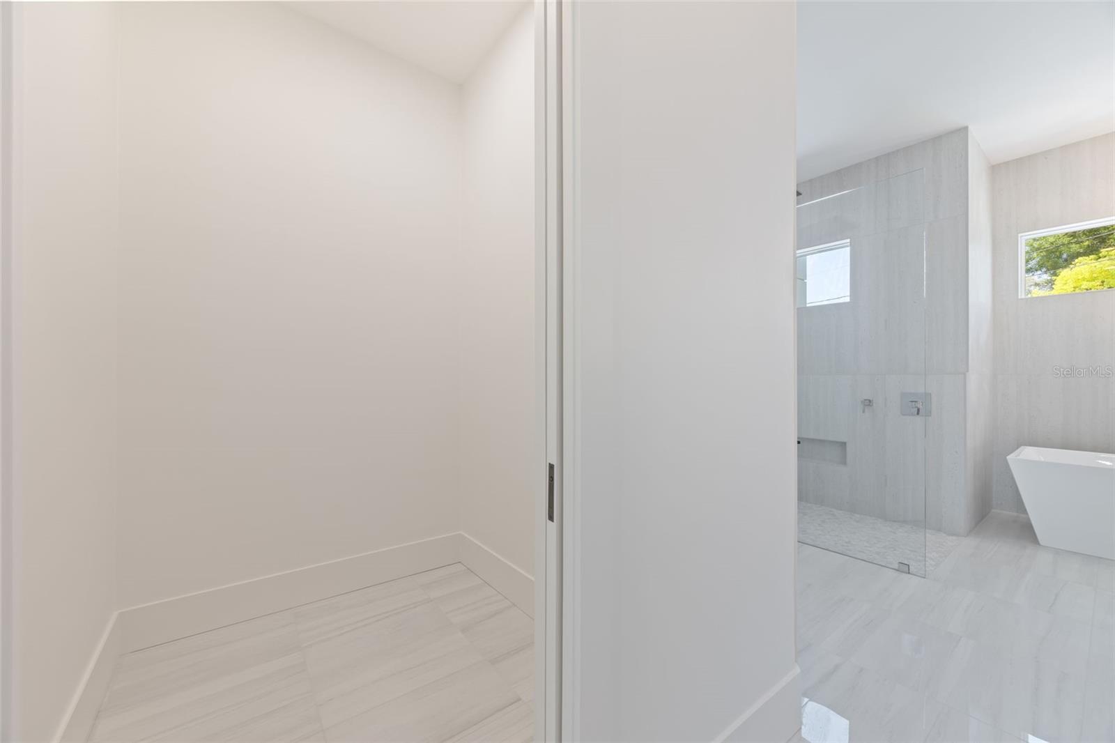 The luxurious primary suite offers a spa-inspired retreat featuring a freestanding soaking tub, oversized walk-in shower with rain head and handheld shower, premium Italian tile, designer fixtures, and thoughtful custom details throughout.