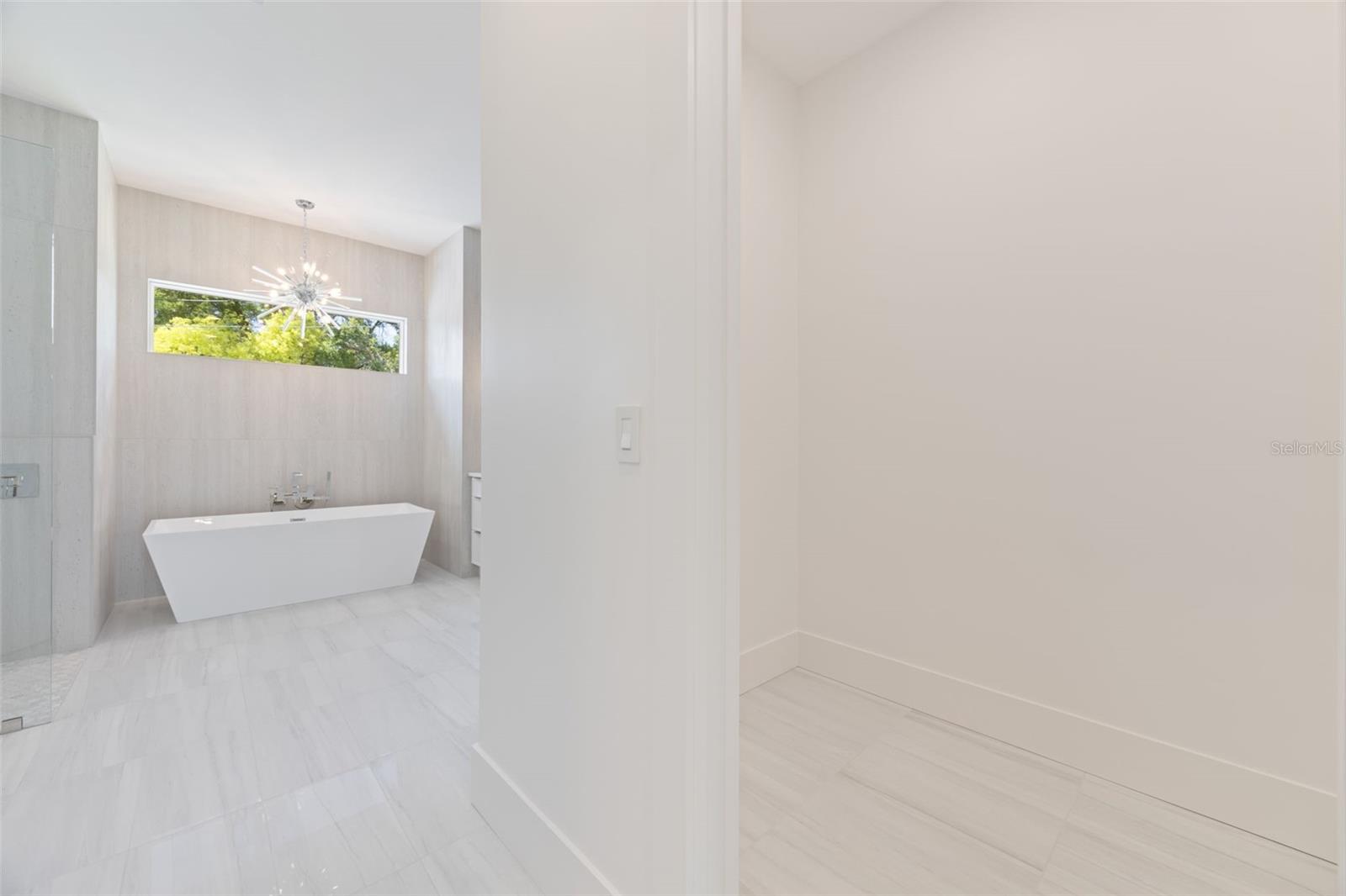 The luxurious primary suite offers a spa-inspired retreat featuring a freestanding soaking tub, oversized walk-in shower with rain head and handheld shower, premium Italian tile, designer fixtures, and thoughtful custom details throughout.