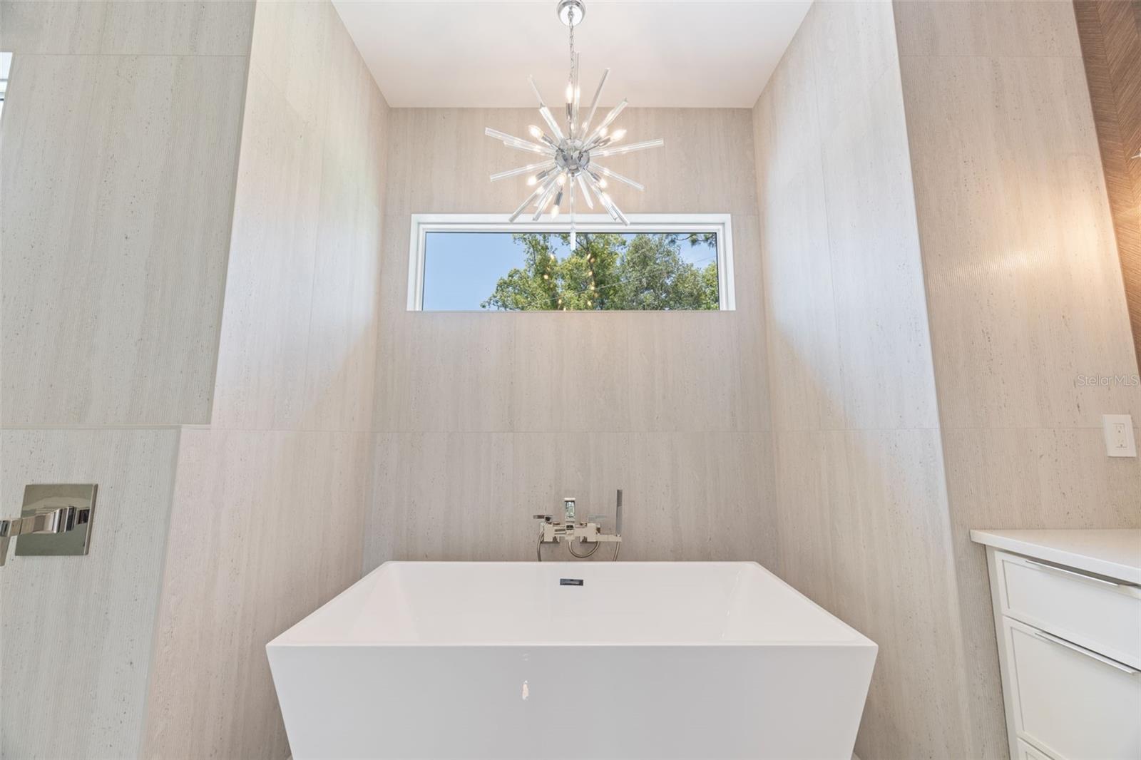 The luxurious primary suite offers a spa-inspired retreat featuring a freestanding soaking tub, oversized walk-in shower with rain head and handheld shower, premium Italian tile, designer fixtures, and thoughtful custom details throughout.
