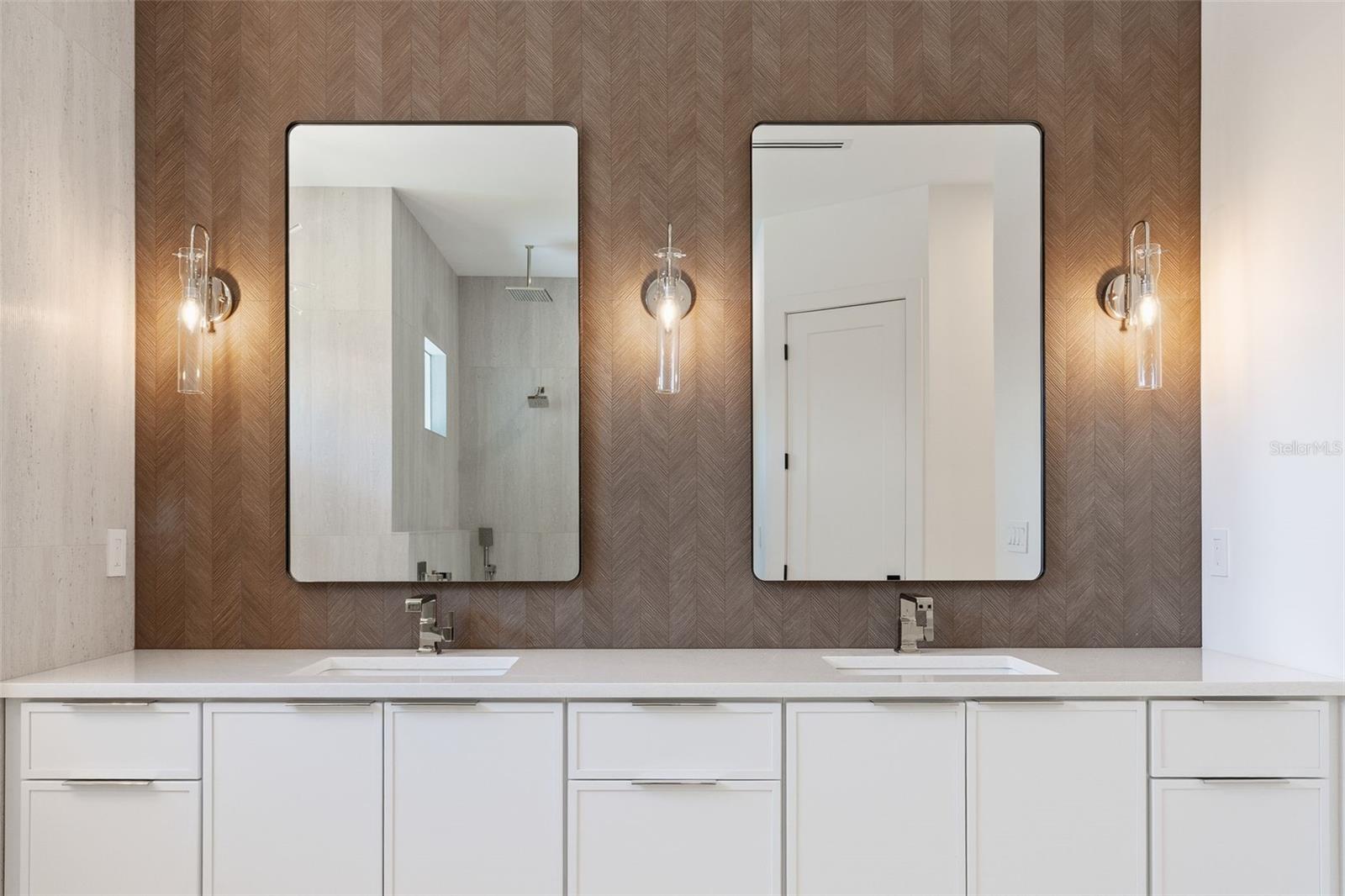 The luxurious primary suite offers a spa-inspired retreat featuring a freestanding soaking tub, oversized walk-in shower with rain head and handheld shower, premium Italian tile, designer fixtures, and thoughtful custom details throughout.