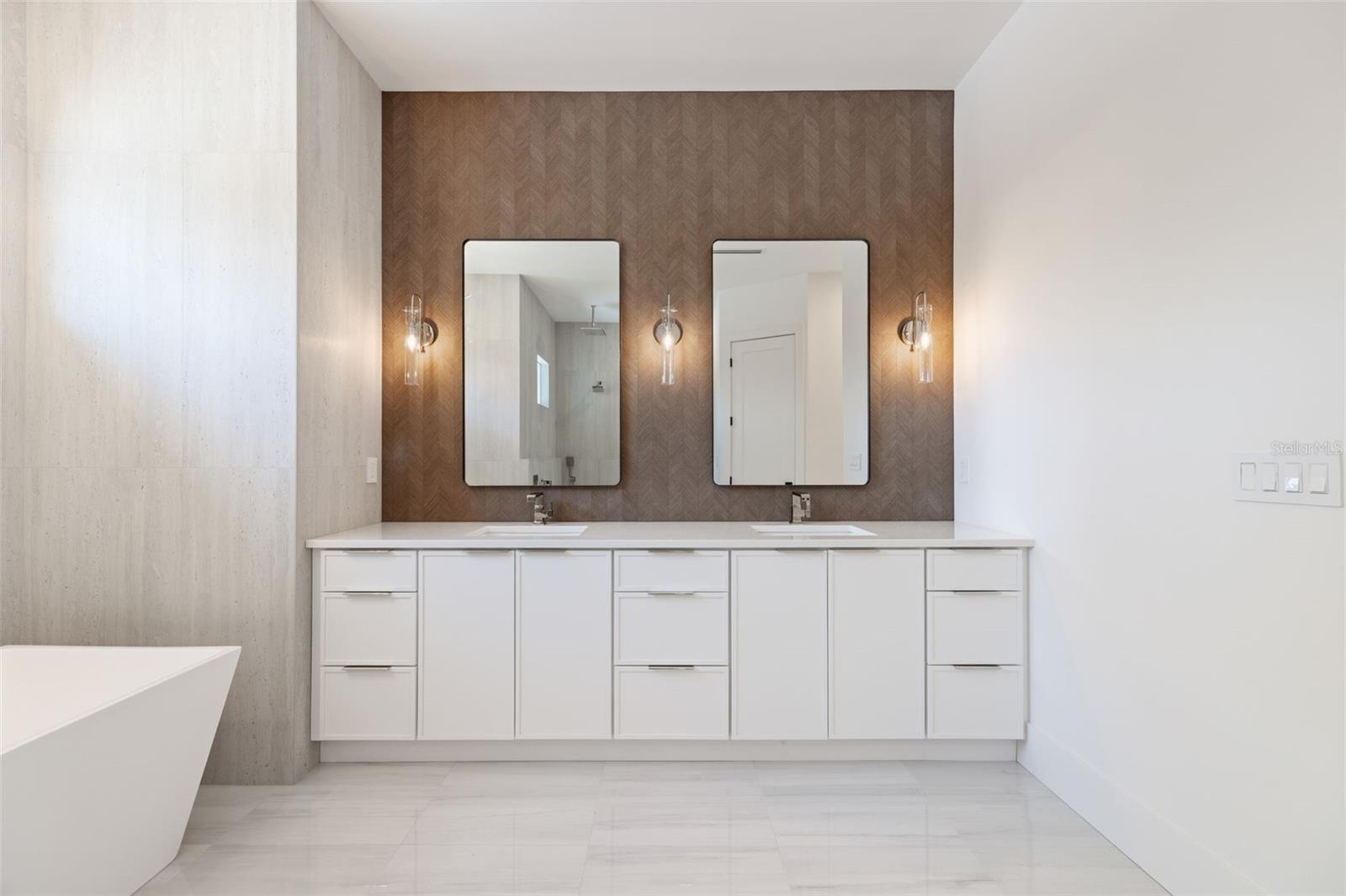 The luxurious primary suite offers a spa-inspired retreat featuring a freestanding soaking tub, oversized walk-in shower with rain head and handheld shower, premium Italian tile, designer fixtures, and thoughtful custom details throughout.