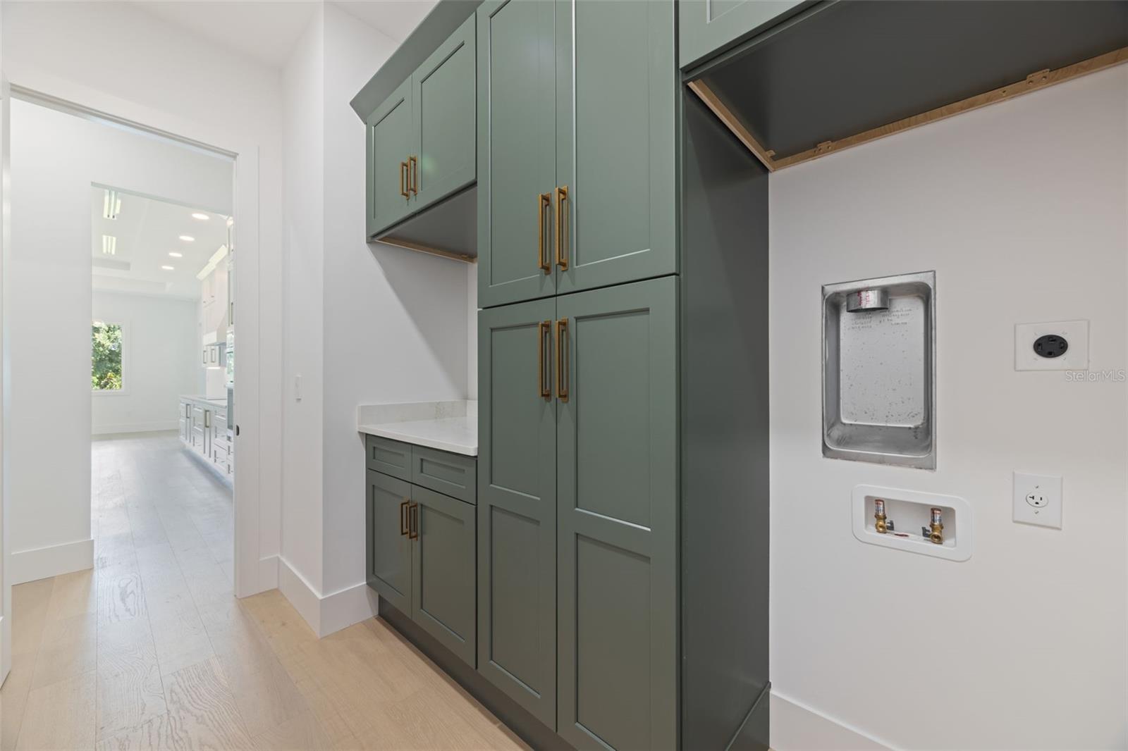 Designed with both beauty and functionality in mind, the laundry room offers elegant Shaker Ivy cabinetry, abundant storage with tall cabinets, stackable washer and dryer hookups, and a pre-plumbed sink base cabinet.