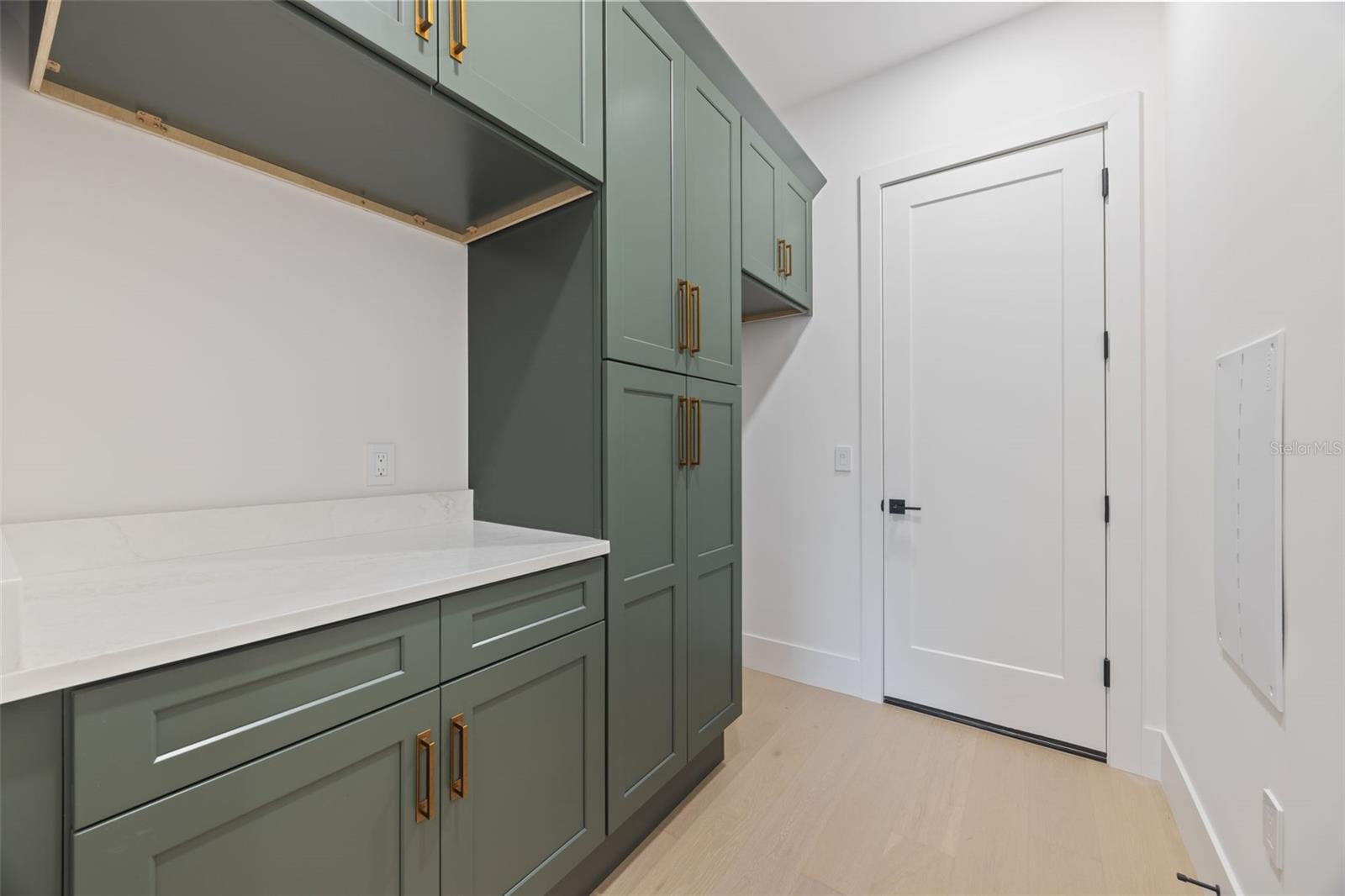 Designed with both beauty and functionality in mind, the laundry room offers elegant Shaker Ivy cabinetry, abundant storage with tall cabinets, stackable washer and dryer hookups, and a pre-plumbed sink base cabinet.