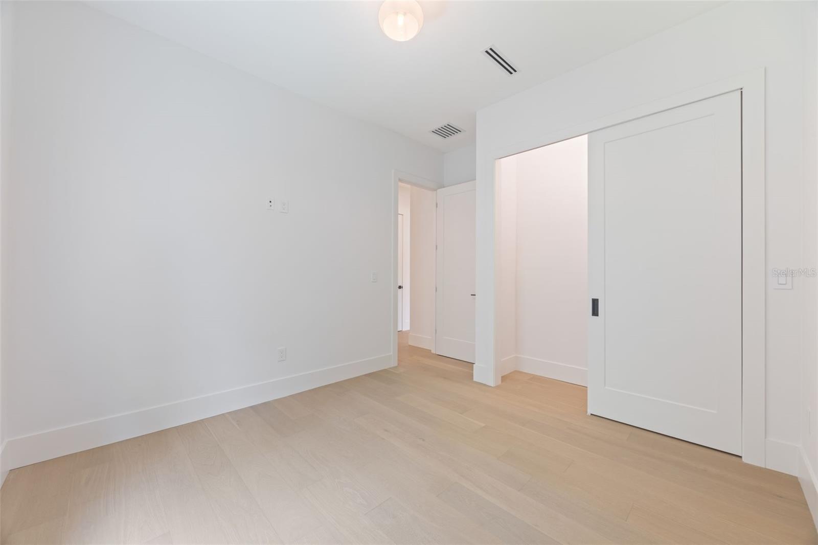 Spacious bedroom 3 with impact-rated window, solid-core door, and convenient access to a full bath.
