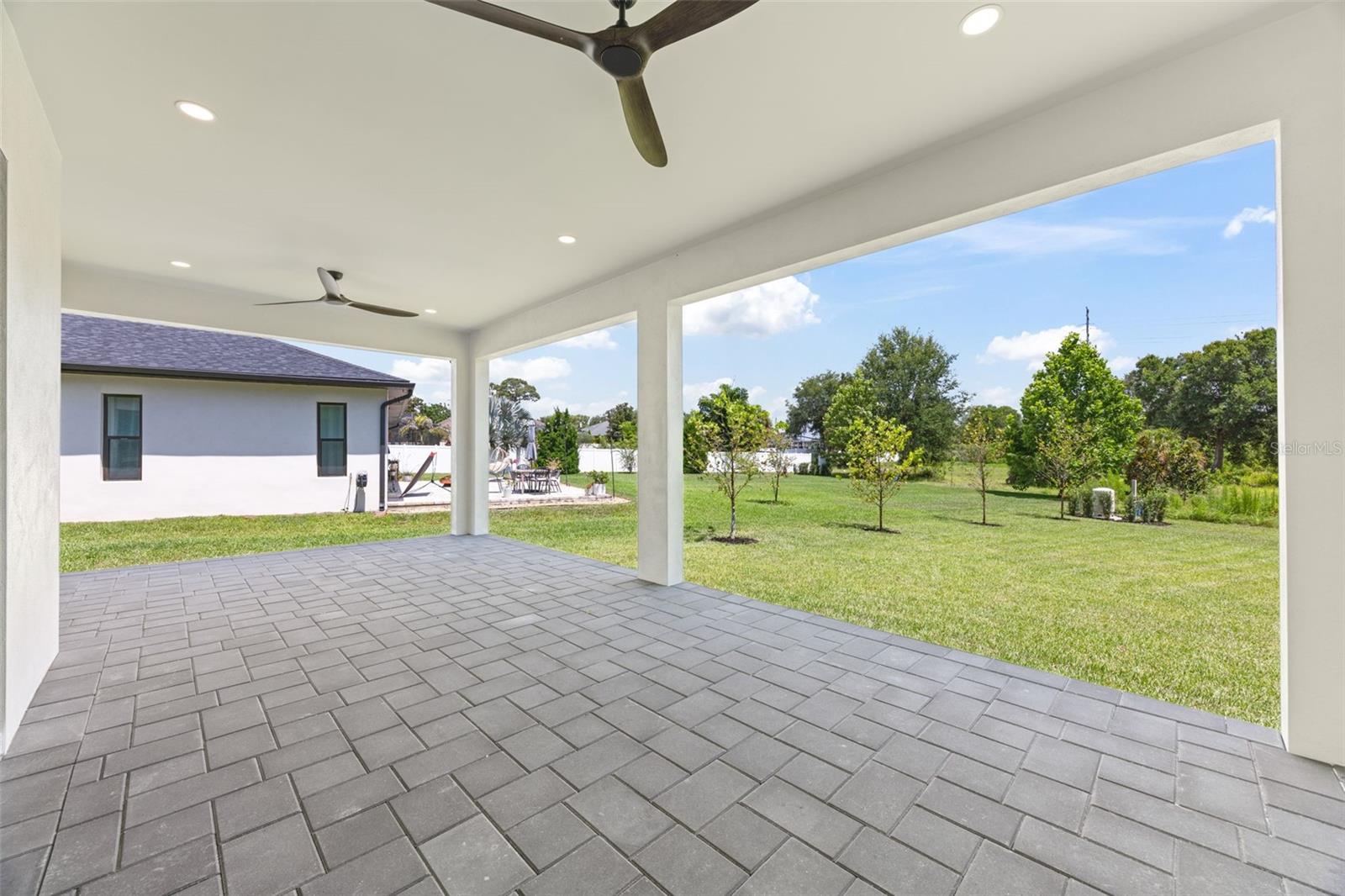 Covered paver lanai, pre-plumbed for a future outdoor kitchen, overlooking the beautifully landscaped yard with premium St. Augustine sod and mature native pine trees.
