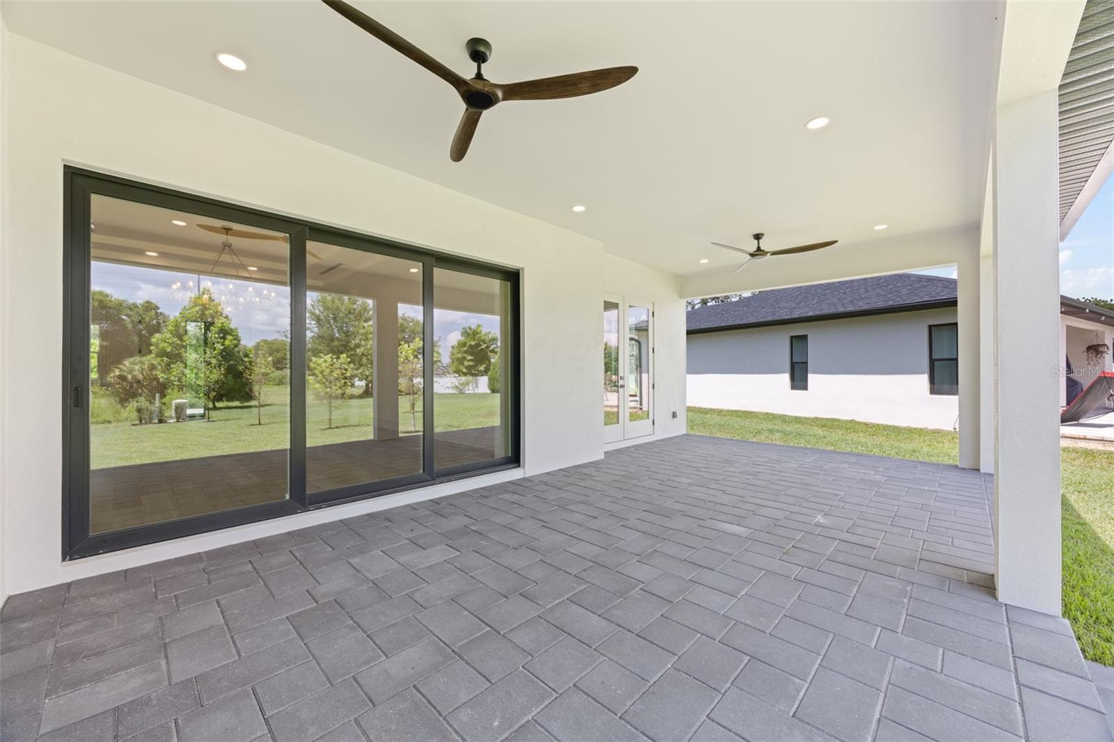Covered paver lanai, pre-plumbed for a future outdoor kitchen, overlooking the beautifully landscaped yard with premium St. Augustine sod and mature native pine trees.